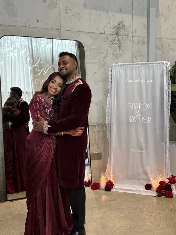 Couple embracing beside their engagement welcome sign